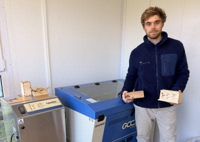 Joseph holding two personalised engraved pet caskets beside the laser engraving machine at Cherry Tree